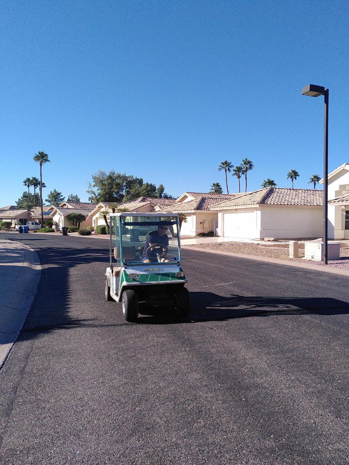 A man driving a golf cart towards the camera