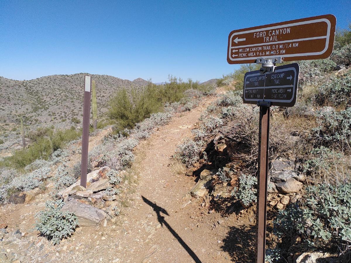 Signs at a trail fork, detailing various routes and distances