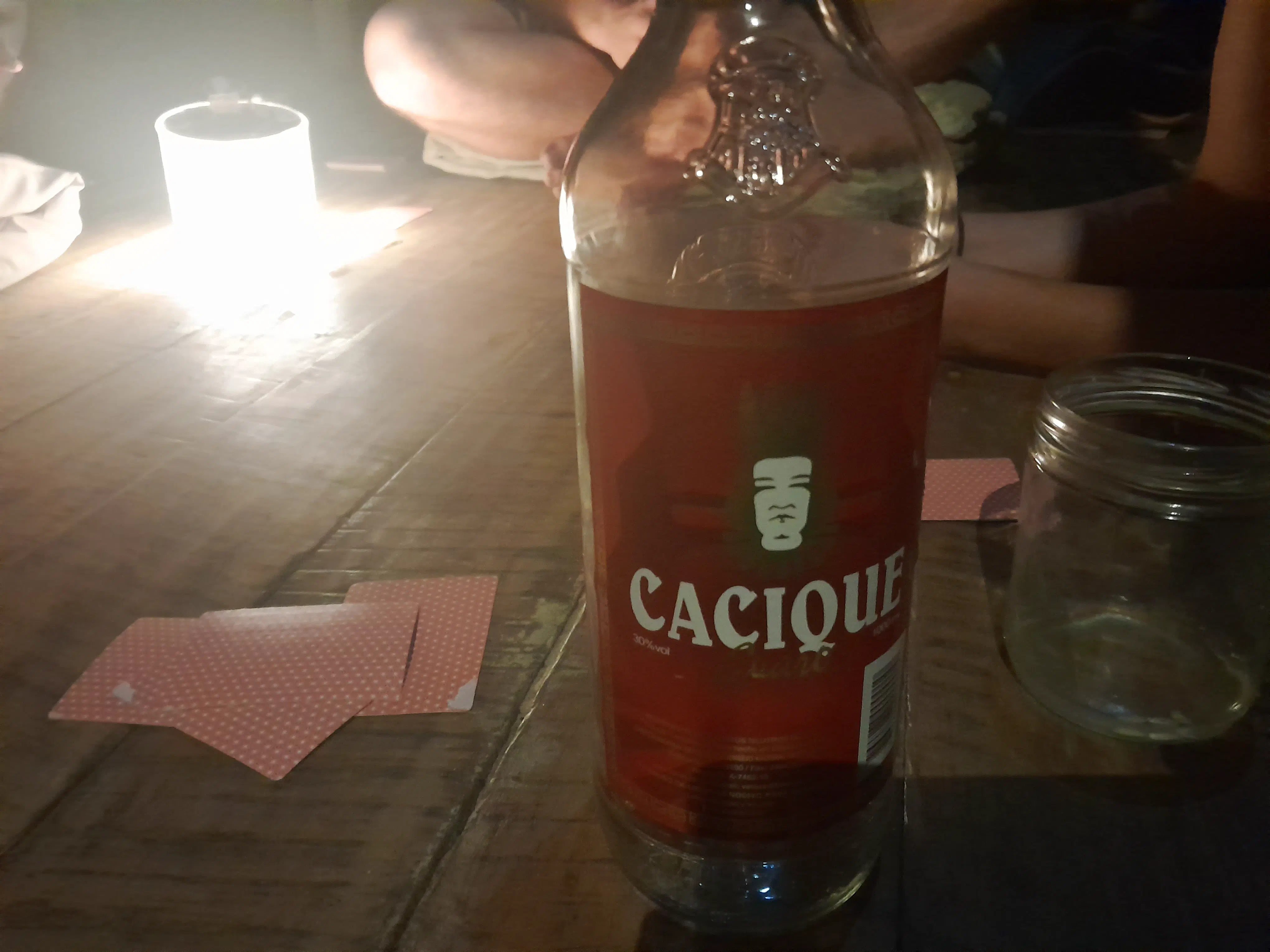A bottle of cacique with playing cards besides it