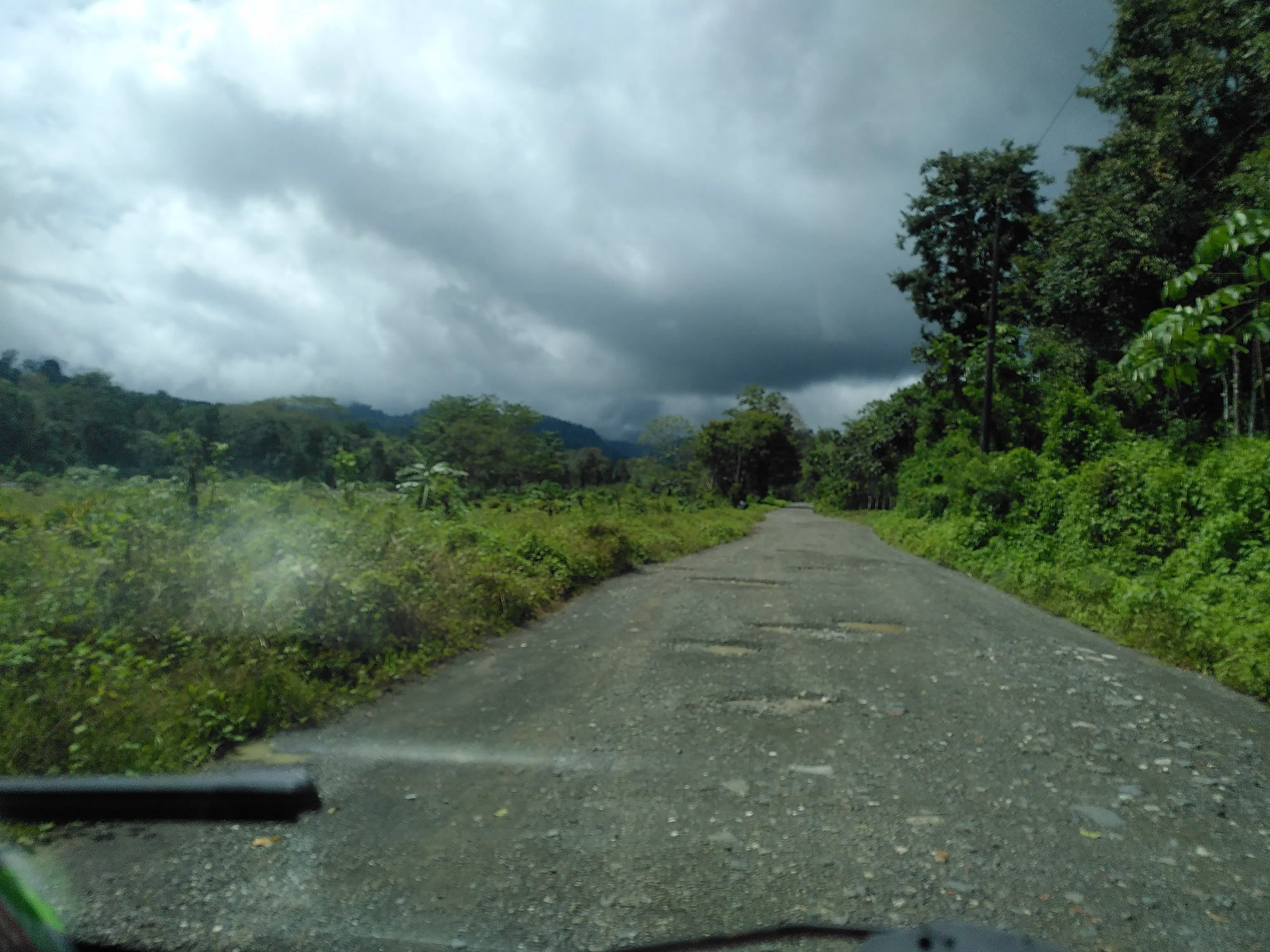 The view out of the windshield of a minibus, looking down a potholed dirt road