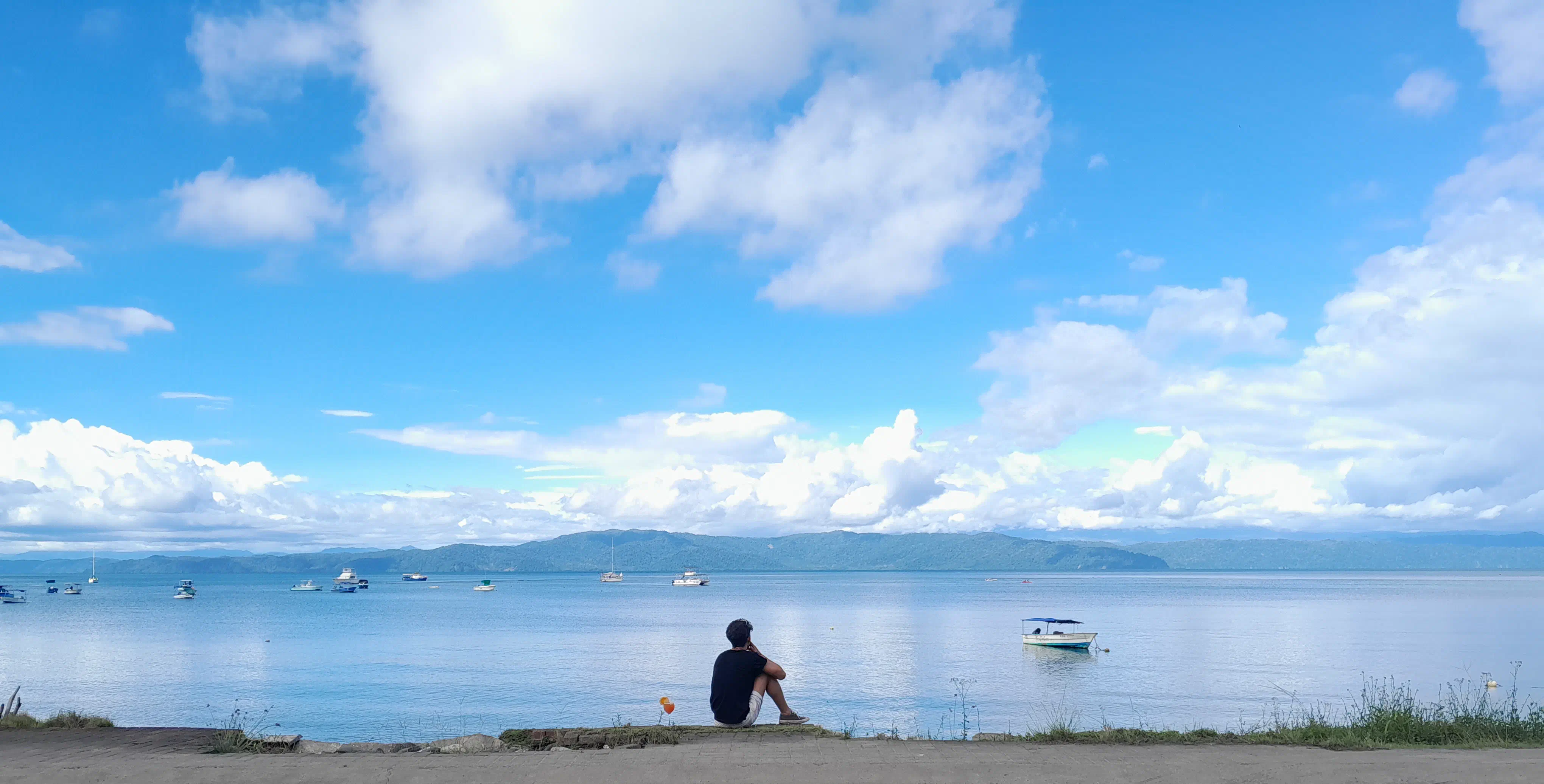 A man sitting with a cocktail in front of an large expanse of water