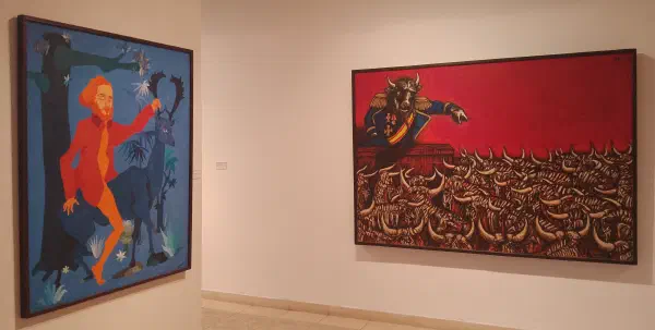 An orange man rides a blue stag through a forest at night-time