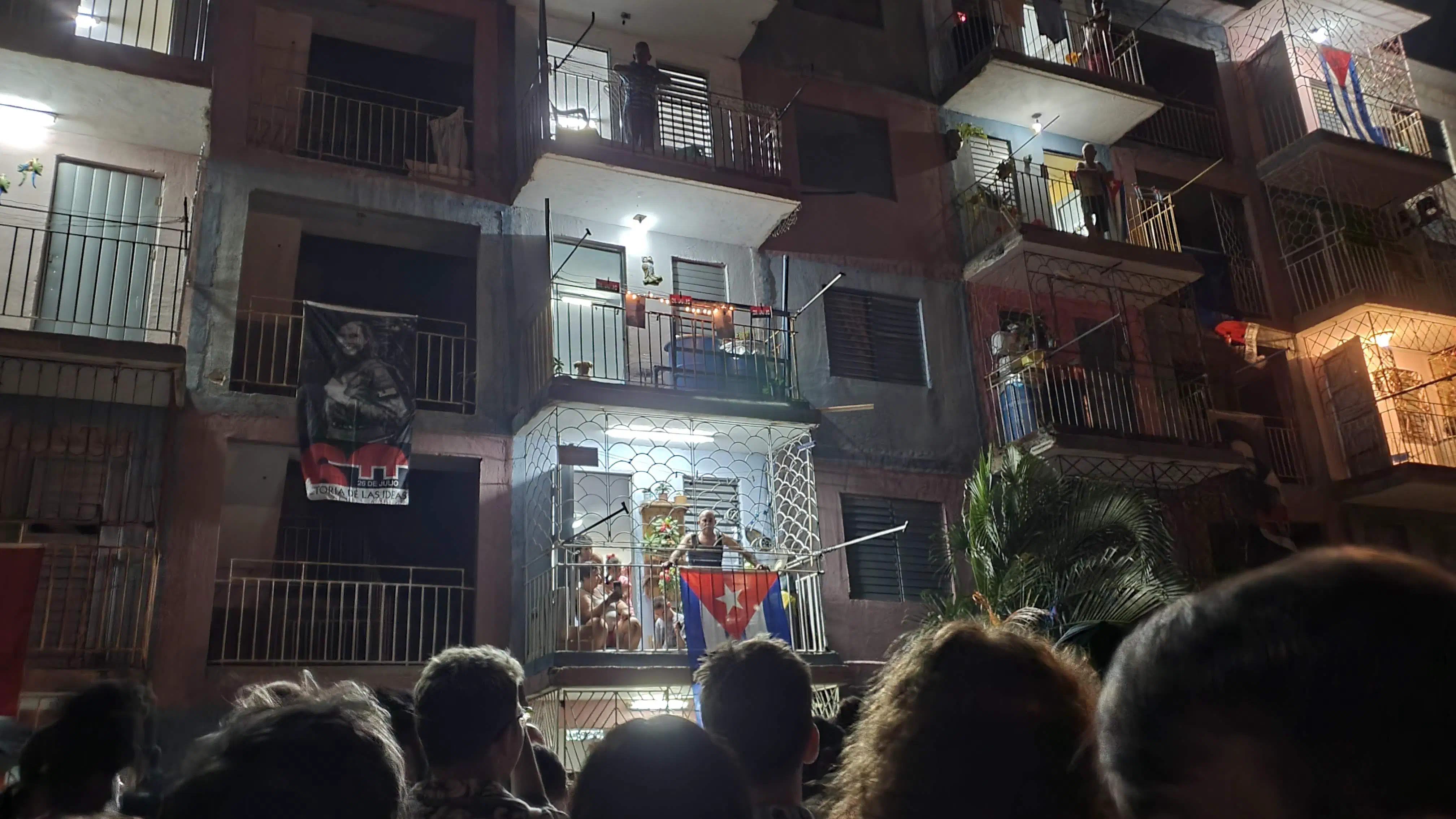 A block party taking place outside a block of flats draped with flags and other symbols from the Cuban Revolution
