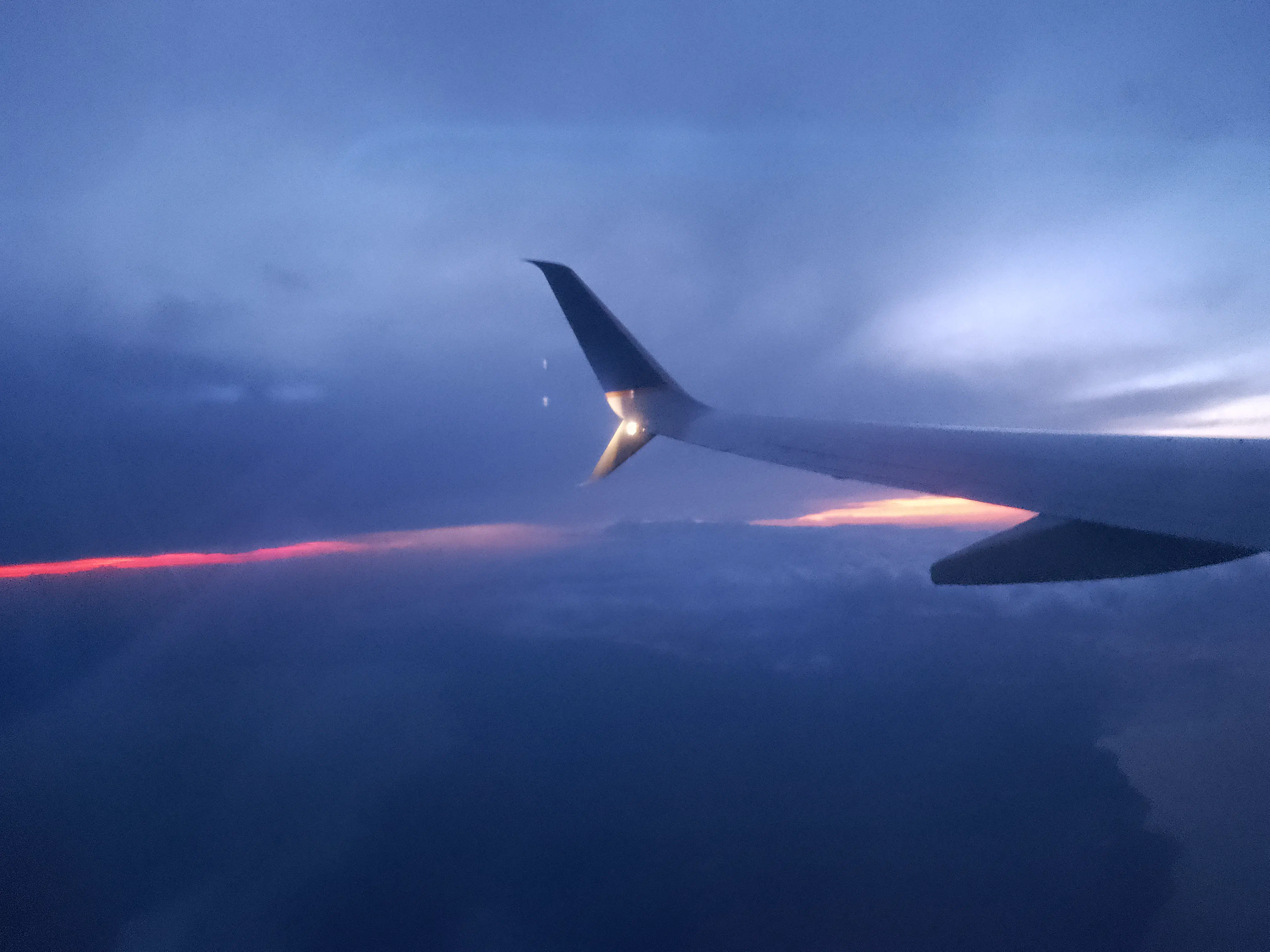 The wing of an aeroplane seen through the window, looking out over the sun rising over Cuba