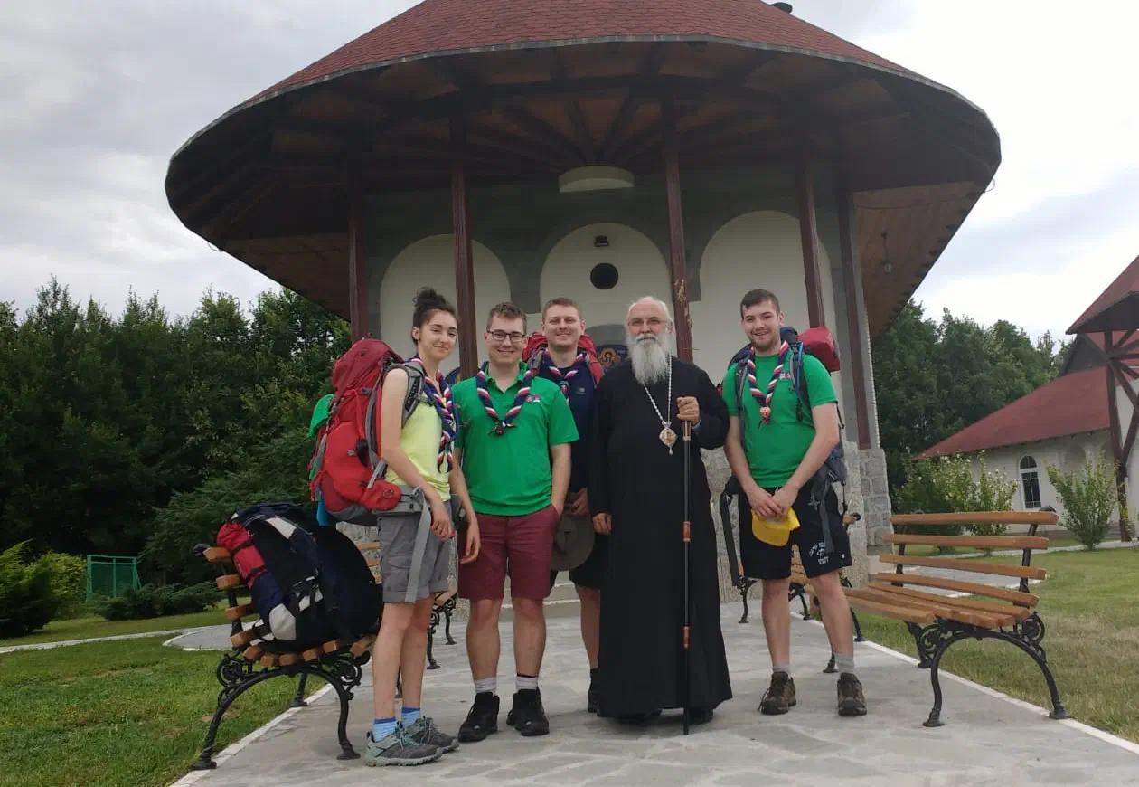 Five people standing in front of a church, one dressed in the robes and regalia of a Serbian Orthodox archbishop