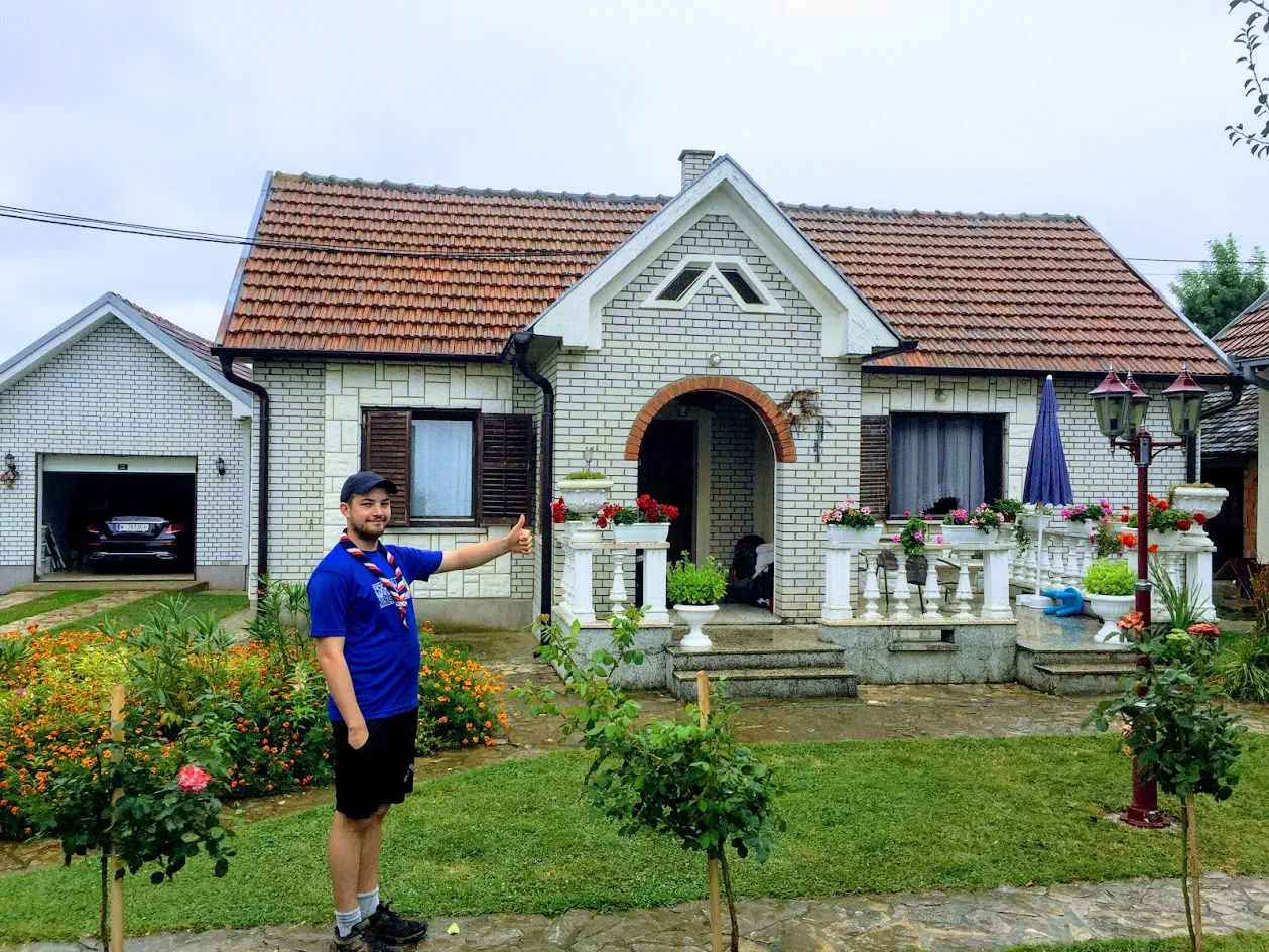 A man standing in front of a beautiful house, giving a thumbs up