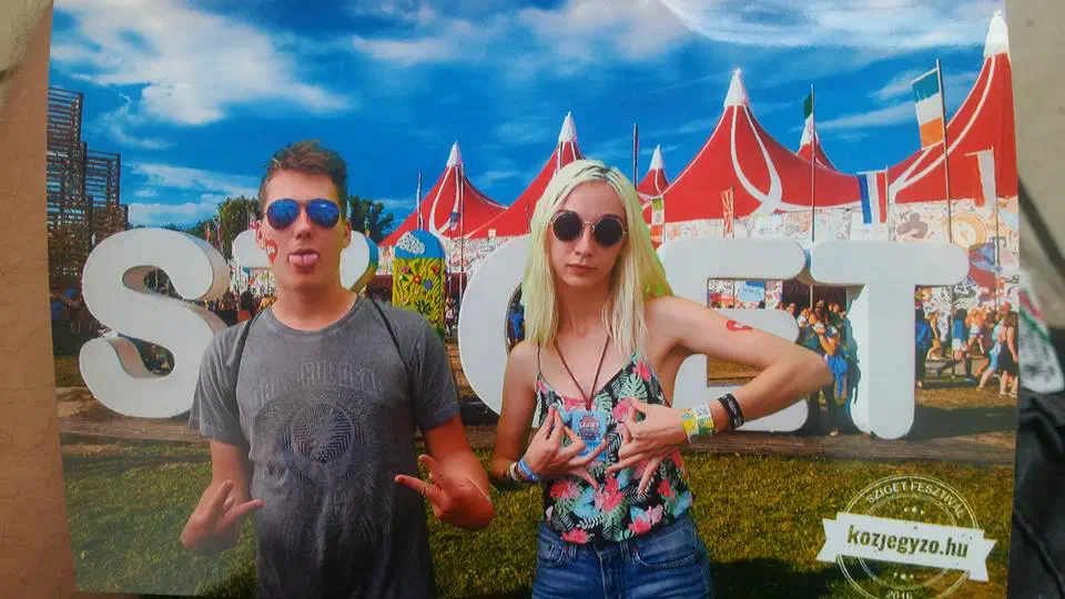 Two people standing in front of a free-standing sign reading ‘Sziget’