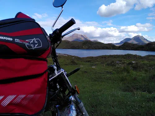 A monkey bike in the foreground, dwarfed by mountains in the background