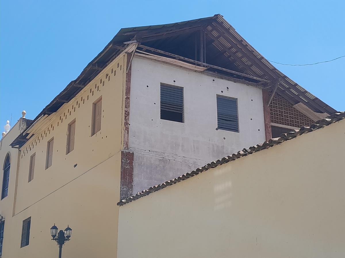 A building, its walls dotted with bullet holes