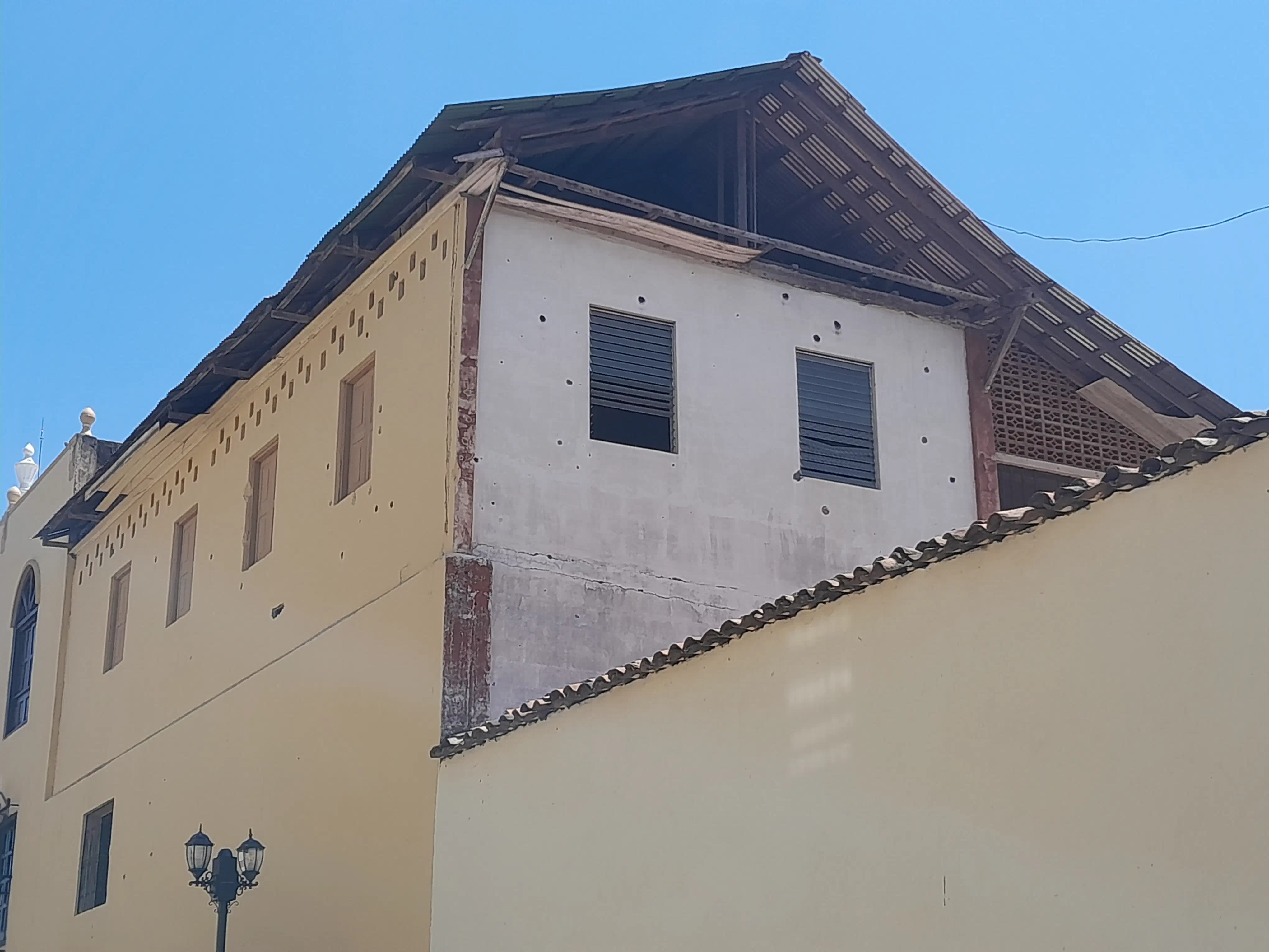 A building, its walls dotted with bullet holes