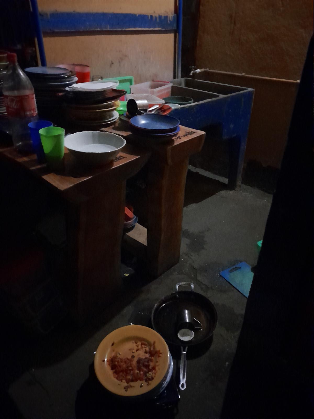 A kitchen area piled high with dirty dishes, including on the floor