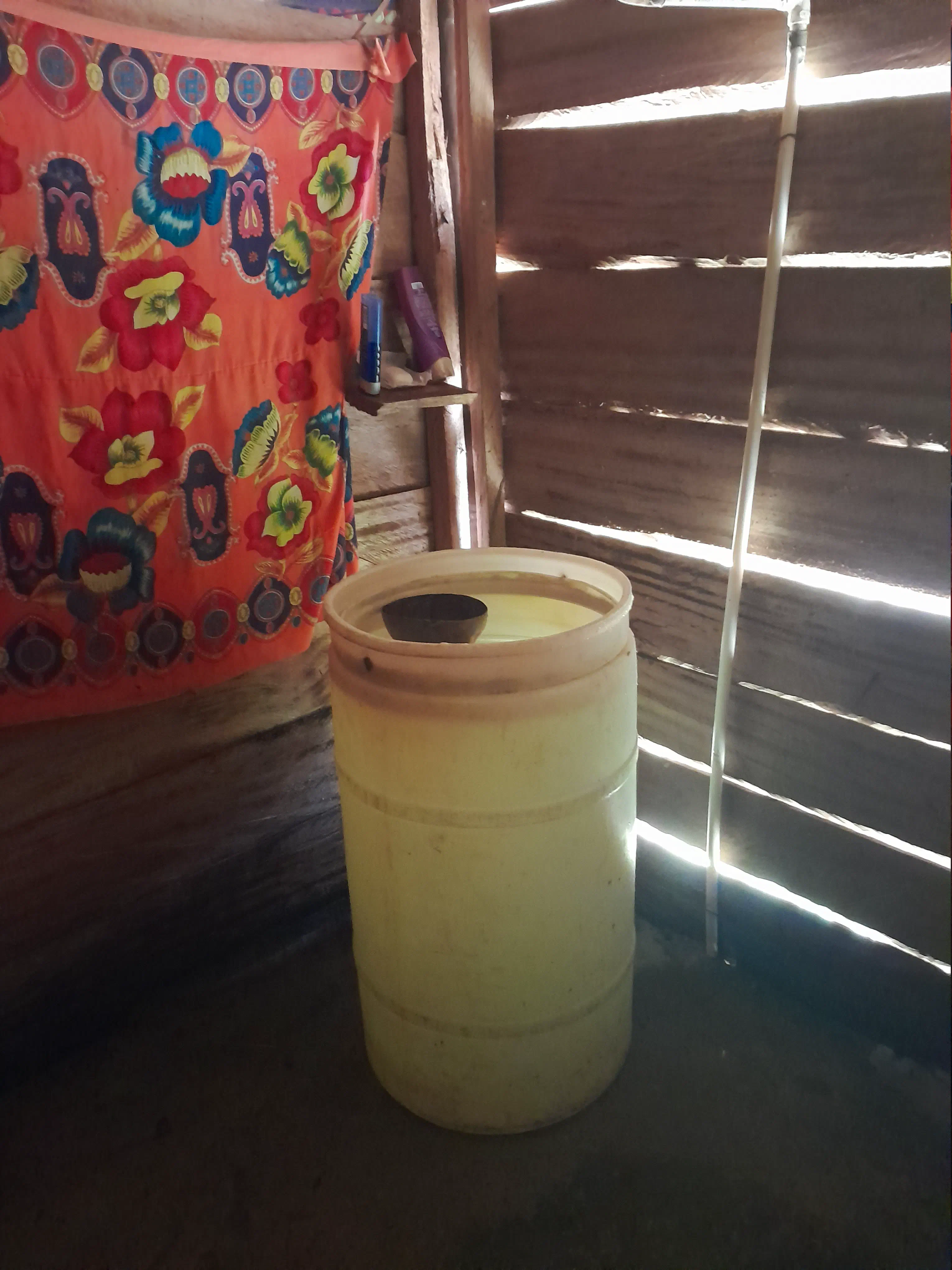 A large water barrel with a halved coconut shell floating in it