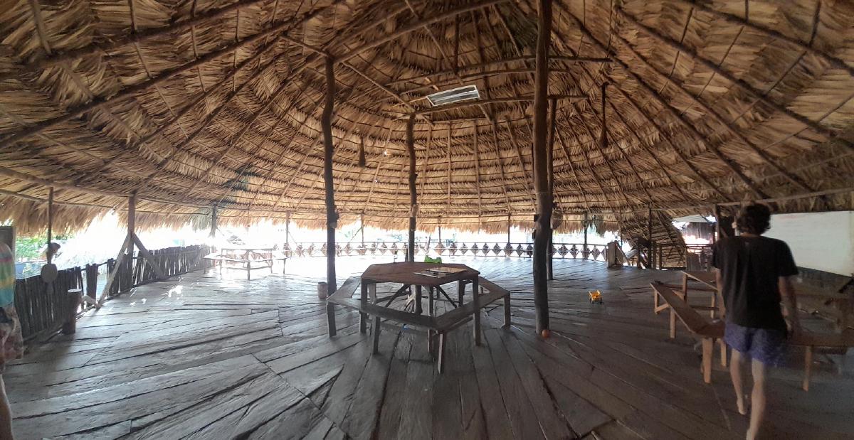 The inside of a large wooden house with a thatched roof