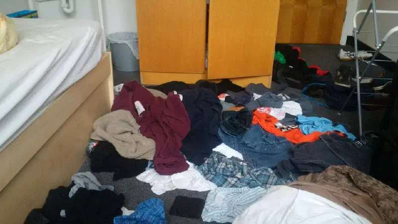 Clothes covering the floor of a bedroom