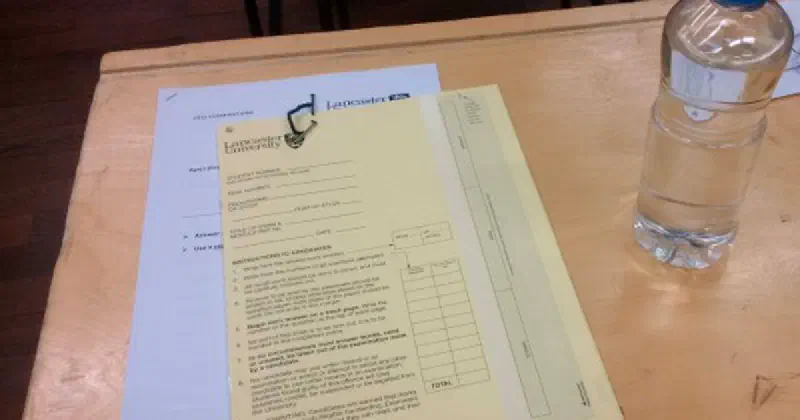 An exam paper on a desk with a bottle of 'water' beside it