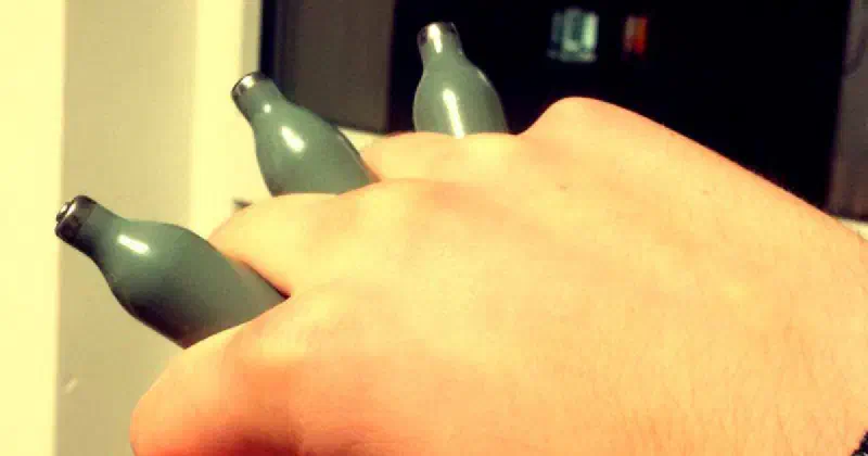 A hand with nitrous canisters held between the fingers