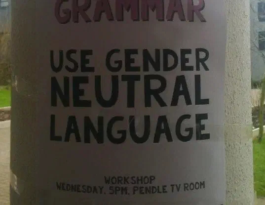 A poster on a piller that reads 'Use gender neutral language'
