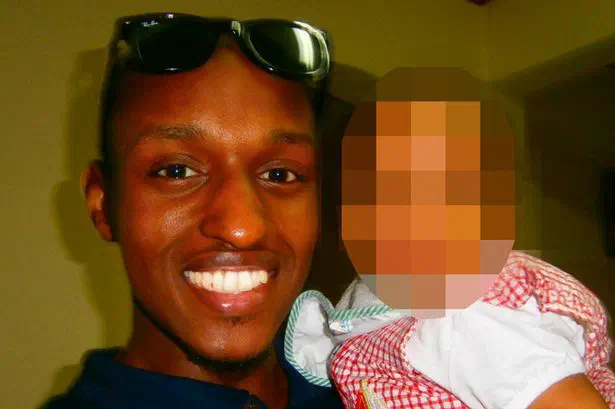 Man holding a baby, whose face is censored