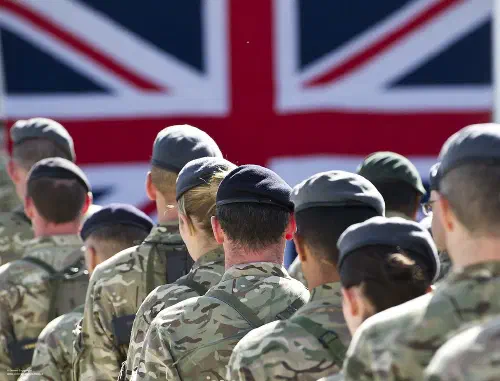 British Army soldiers marching with a UK flag in the background