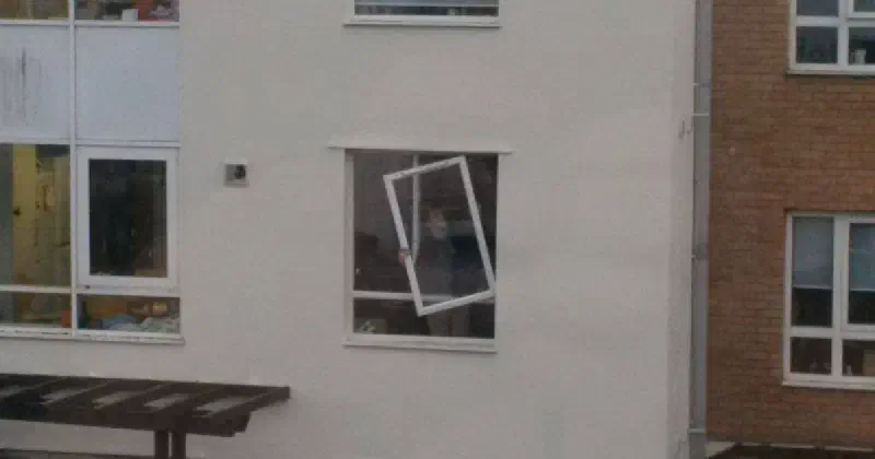 A window partially hanging from its frame