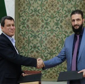SDF commander Mazloum Abdi shaking hands with Syrian Transitional Government President al-Sharaa